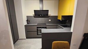 Eine moderne Küche mit einer zentralen Kochinsel, einem eingebauten Backofen und einer schwarzen Dunstabzugshaube.
