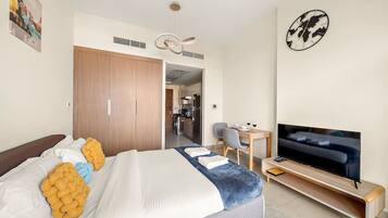 Een moderne hotelkamer met een bed, een televisie, een bureau en een eethoek.
