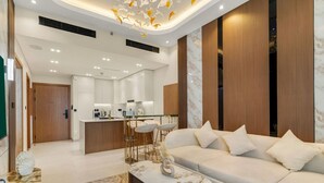 A modern living room with a sofa, coffee table, and a kitchen in the background. - Timeless Luxury 1BR Apartment Near Dubai Marina & Iconic Palm Jumeirah (JVC)