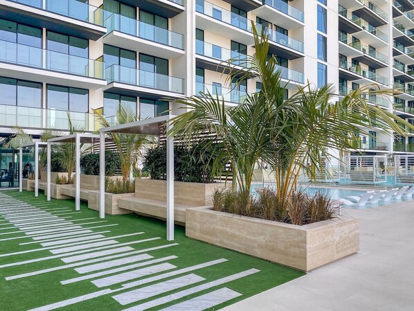 Un hôtel moderne doté d’une piscine sur le toit, d’un espace extérieur aménagé et d’un jardin luxuriant.
