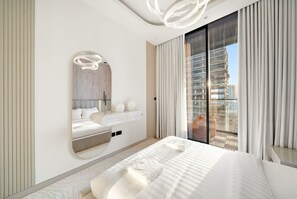 Une chambre moderne avec un grand lit, une coiffeuse intégrée, un grand miroir et un balcon offrant une vue sur la ville.