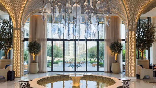 A spacious lobby with a central fountain, large windows, and modern decor.