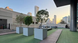 A rooftop garden with artificial grass, planters, and seating areas.