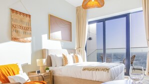 Ein modernes Hotelzimmer mit einem großen Bett, einer Essecke und einem Balkon mit Aussicht.
