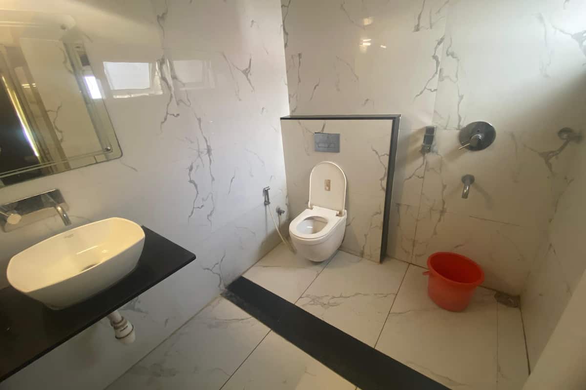 Un baño con un lavabo blanco, un inodoro y un cubo rojo.