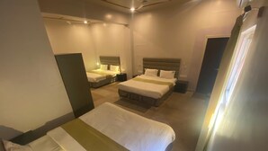 A hotel room with two single beds and a larger bed, all with white linens and headboards. - Shri Sai Palace inn (Chikkamagaluru)