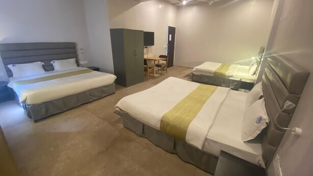 A hotel room with two beds, a desk, and a wardrobe. - Shri Sai Palace inn (Chikkamagaluru)