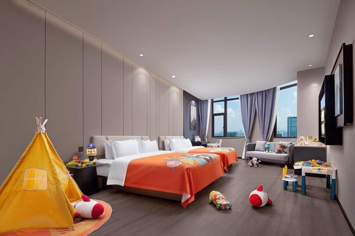 Une chambre d’hôtel moderne équipée d’un grand lit, d’un canapé, d’une télévision et d’un espace de jeux avec des jouets.