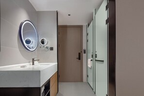 A modern bathroom with a large mirror, a vanity with a sink, and a glass shower enclosure. - LAN HOTEL (Chengdu)