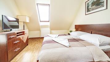 Un dormitorio con cama, televisor, cómoda y ventana.