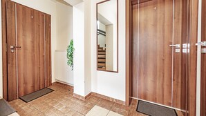 Un couloir avec des portes en bois numérotées 3 et 4, un radiateur blanc et un escalier visible dans le reflet du miroir.