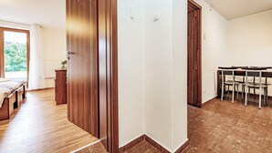 Une chambre moderne avec un plancher en bois, une grande fenêtre et un coin repas comprenant des chaises et une table.
