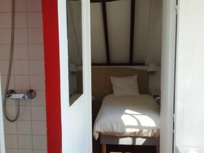 Habitación de hotel con ducha, cama y ventana con cortinas.
