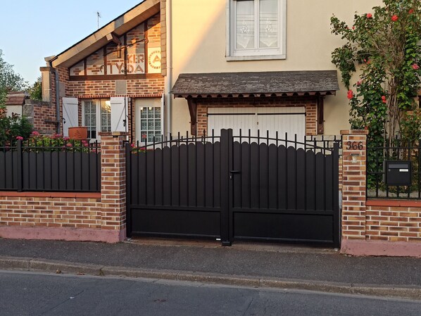 A brick building with a black metal gate, a window with a white frame, and a brick mailbox with the number 366. - Independent Apartment in Saran, near Orléans (Saran)