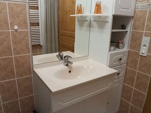 A bathroom with a white sink, a mirror, and a wooden door.