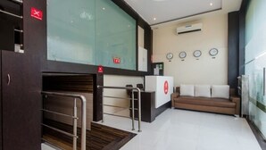 A modern hotel lobby with a reception desk, a sofa, and a glass partition. - Hotel Venture Grand (Mumbai)