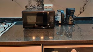 A kitchen with a black microwave, a coffee maker, and a gas stove.