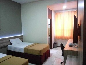 A hotel room with two beds, a desk, and a chair. - Wisma Sejahtera Hotel (Magelang)
