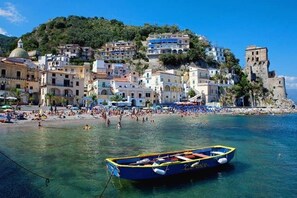 A coastal town with buildings on a hillside, a beach, and a boat in the water. - Ammare House (Cetara)