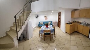 Un espacio habitable compacto con comedor, cocina y una escalera que conduce a un nivel superior.
