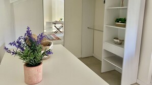 Een kamer met een witte tafel, een kamerplant en een witte wandplank.