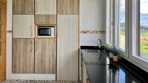 Una cucina con mobili in legno, un forno a microonde, un lavandino e una finestra che si affaccia sulla campagna.