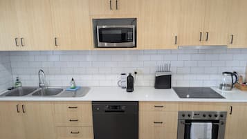 A modern kitchen with wooden cabinets, a stainless steel microwave, a dishwasher, a stove, and a coffee maker.
