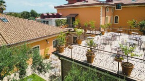 Una terraza en la azotea con plantas en macetas, mobiliario exterior y tejado de baldosas.