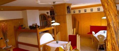 A cozy room with a bunk bed, a dining table with chairs, and a small kitchen area.