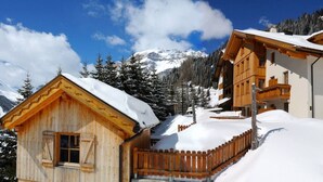 A wooden chalet with a balcony, surrounded by snow-covered mountains and trees. - Design Chalet Zirm - Check-in at Olympia Hotel (Livinallongo del Col di Lana)