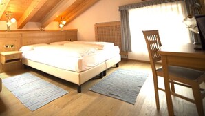 A bedroom with a wooden ceiling, a bed, a desk, and a chair. - Design Chalet Zirm - Check-in at Olympia Hotel (Livinallongo del Col di Lana)