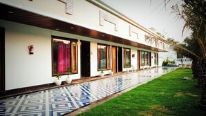 A hotel with a covered walkway, potted plants, and a tiled entrance.