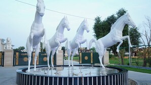 A circular fountain with four white horse statues.