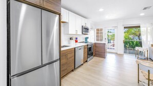 A modern kitchen with stainless steel appliances, white cabinetry, and a wooden countertop. - NEW LISTING! Village Breeze III - Heated Pool, Private Patio, Village and Beach! (Siesta Key)
