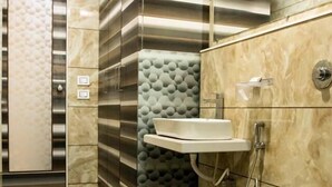 A modern bathroom with a toilet, sink, and shower area. - Hotel Fun City (Navsari)