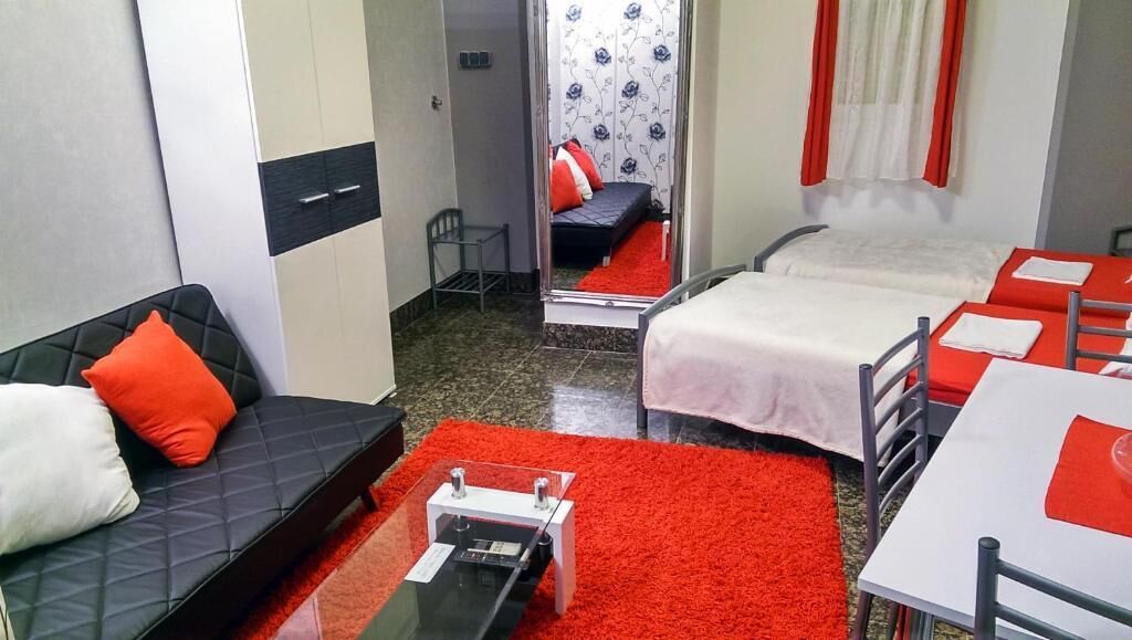 Habitación de hotel con dos camas, un sofá, una mesita y un espejo.