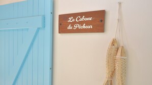 Une enseigne en bois avec une inscription, une porte bleue et une œuvre en macramé accrochée au mur.