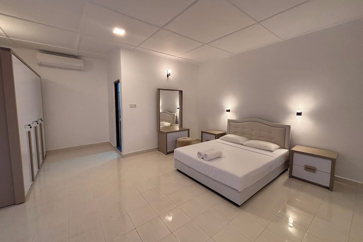 A modern bedroom with a large bed, bedside tables, a mirror, and an air conditioning unit.