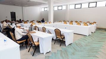 A conference room with long tables, chairs, and attendees.