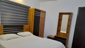 A bedroom with a bed, wooden wardrobe, and a mirror. - Casita Lavender Resort (Vythiri)