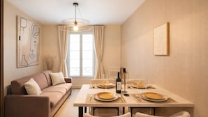 A dining area with a table set for four, a sofa, and artwork on the walls. - Courtois (Paris)