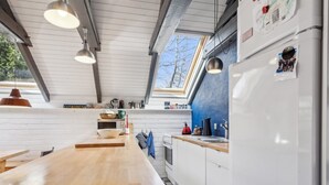 A modern kitchen with a wooden countertop, white cabinets, and a black and white checkered floor.