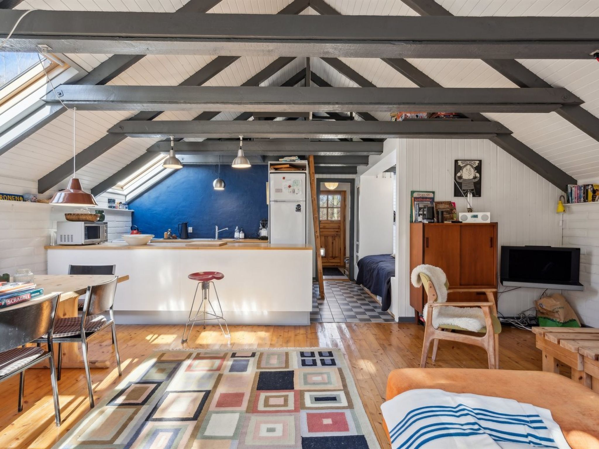 A cozy attic room with a kitchen, a dining area, and a living space.