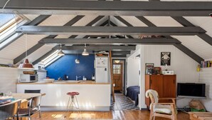 A cozy attic room with a kitchen, a dining area, and a living space.