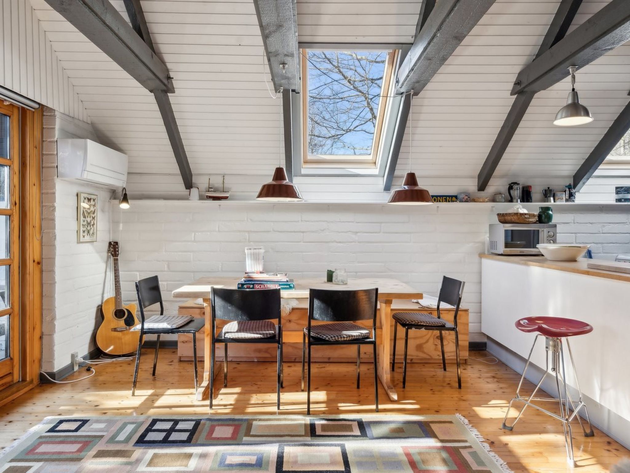 A cozy kitchen with a dining area, featuring a wooden table, chairs, and a view through a skylight.