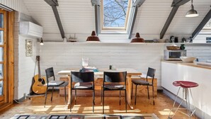 A cozy kitchen with a dining area, featuring a wooden table, chairs, and a view through a skylight.