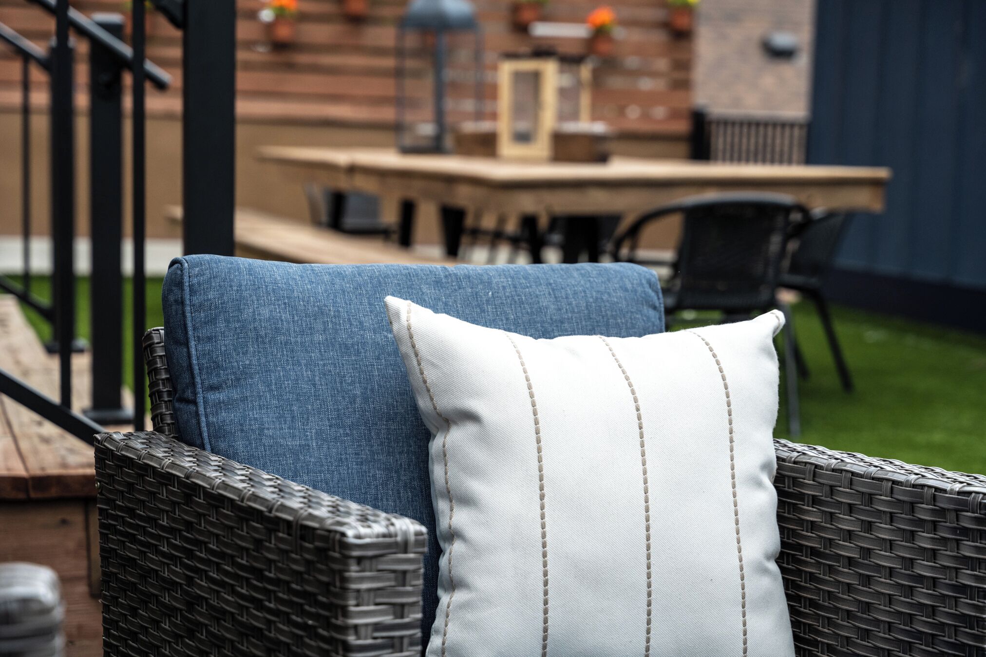 A wicker chair with a blue cushion and a white cushion with vertical stitching.