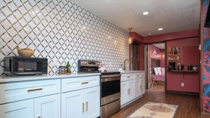 Una cocina con armarios blancos, microondas, horno y pileta.