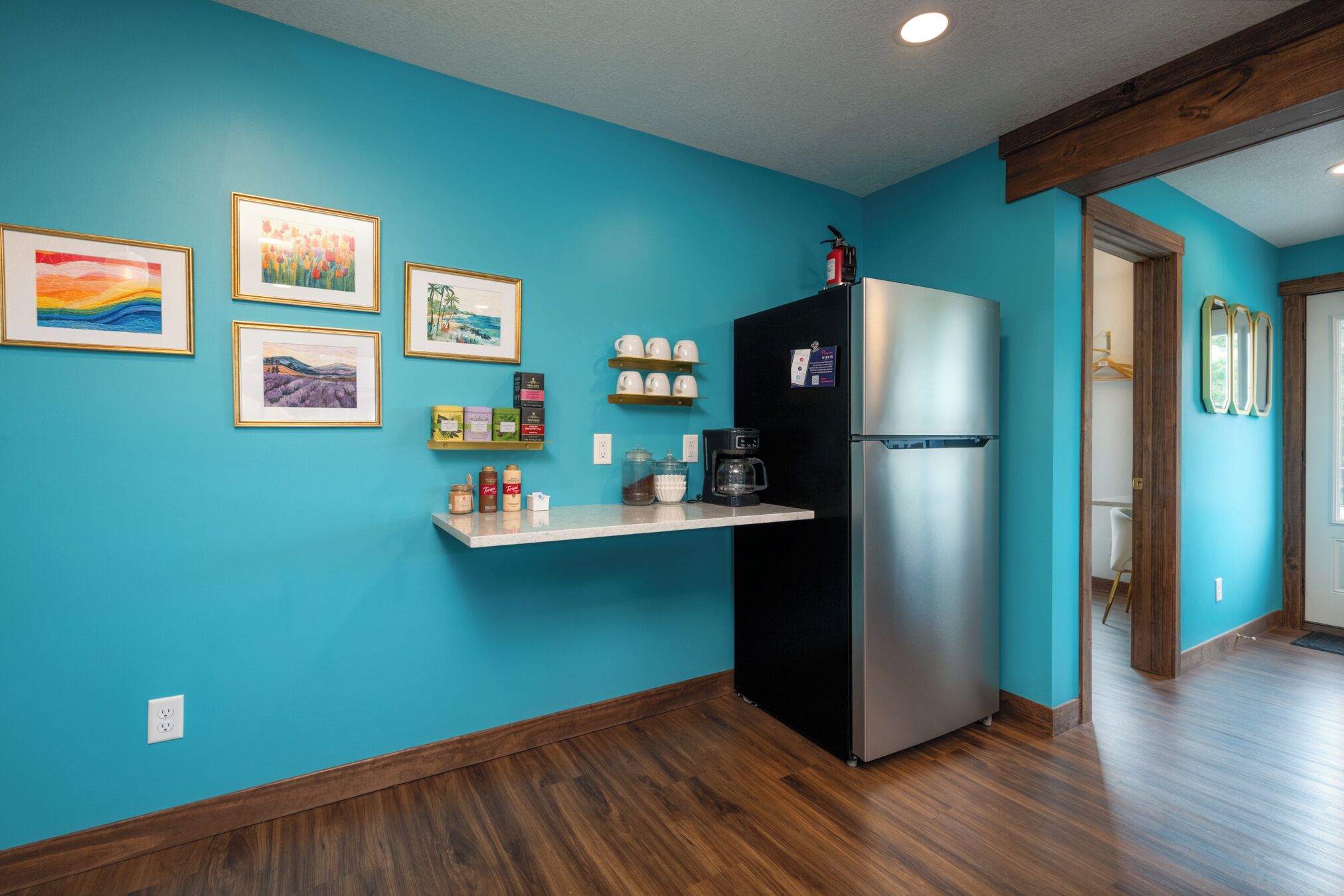 A kitchen with teal walls, a black refrigerator, and a wooden countertop with various items.