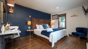 Une chambre d’hôtel moderne avec un grand lit, des lampes de chevet, un bureau avec des articles de toilette et une chaise.